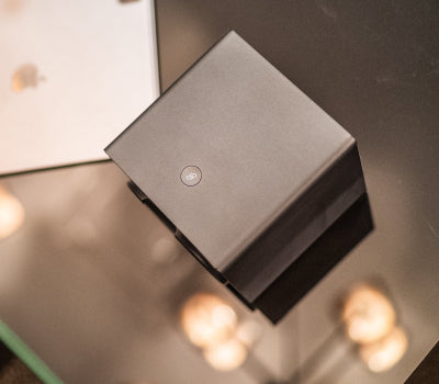 Minimalist black cube on a reflective surface with soft lighting.