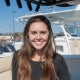 A woman smiling in front of boats at a marina.